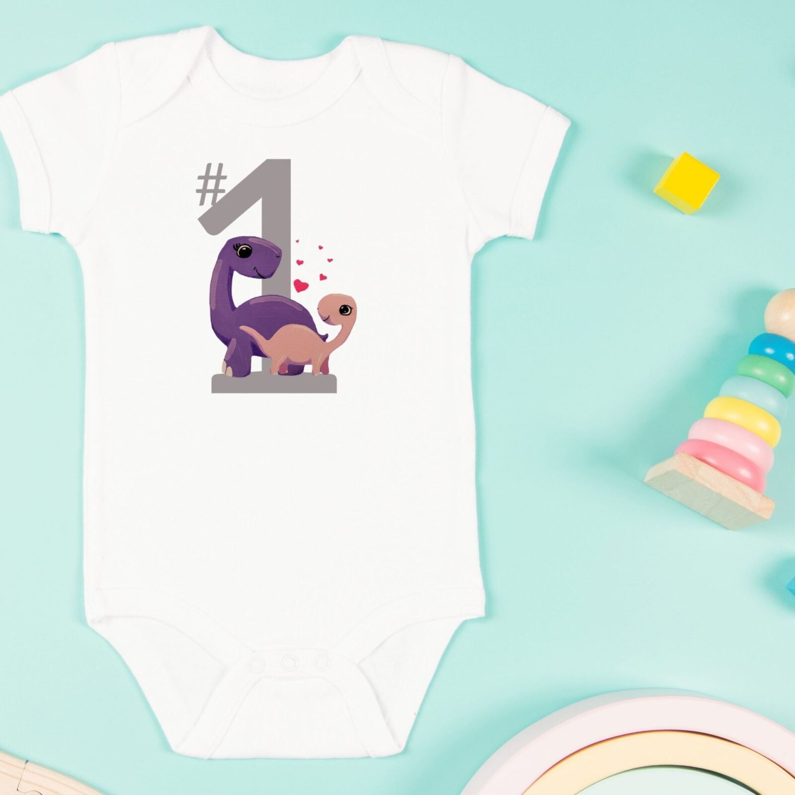 This white baby suit features playful dinosaurs and vibrant red hearts