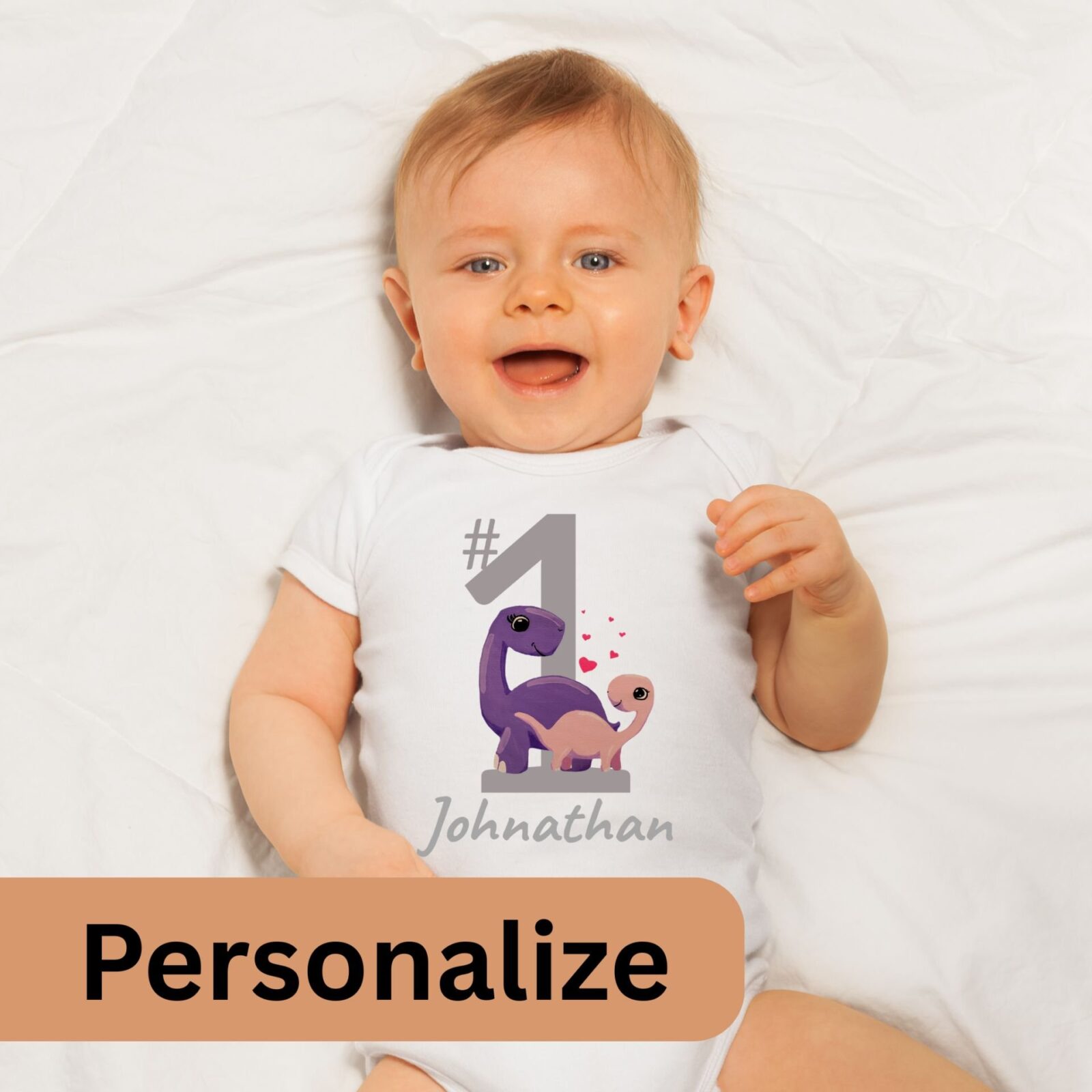 Baby wearing a white summer bodysuit with a dinosaur design, a big number 1 and the baby's name is optional to personalize.