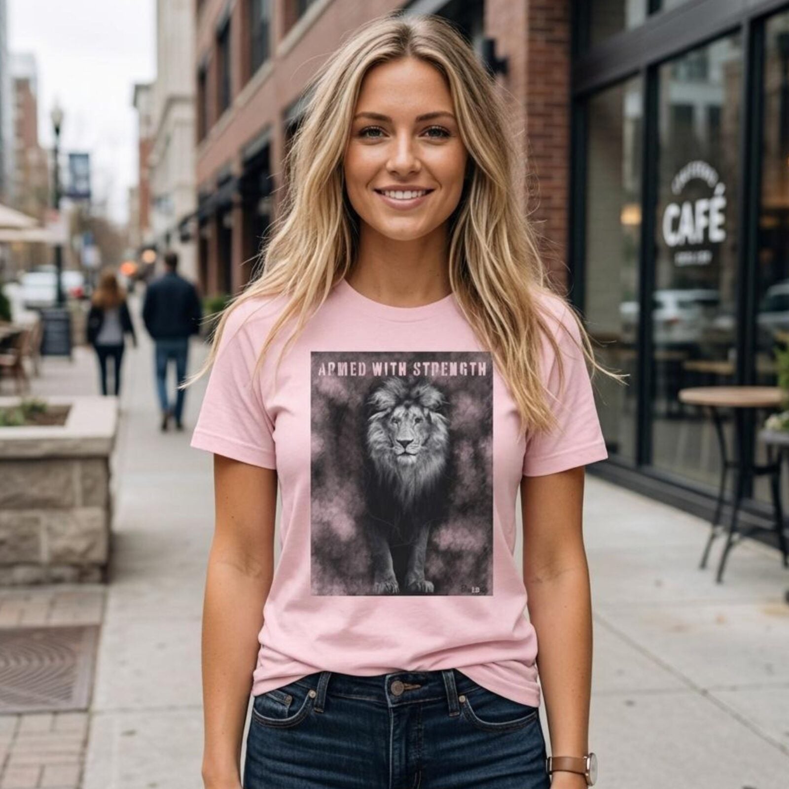A woman wearing a pink Unisex t-shirt with a Lion design. This Christian design includes the word "Armed with Strength".