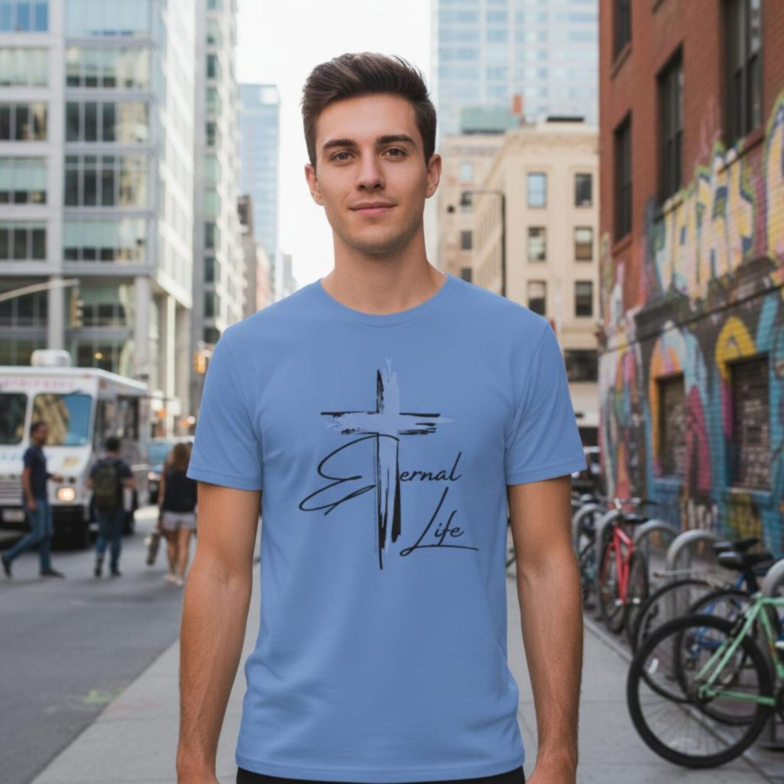 A man wearing a columbia blue unixes t-shirt with a cross design. This plain Christian Cross design includes the text "Eternal Life" and quote Galatians 3:11.
