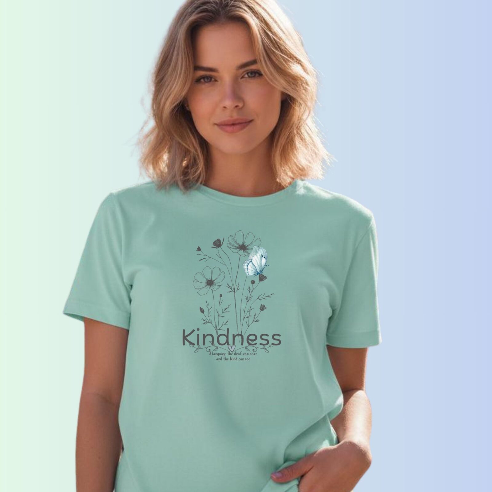 A woman wearing a mint coloured t-shirt with a flower and butterfly design, and the text "Kindness" and "A language the deaf can hear and the blind can see".