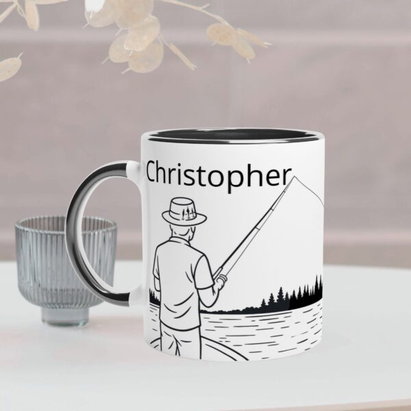 This white mug has a black coloured handle and inside. It has a fisherman design and custom text to personalize it with a person's name on the front of the mug, and on the back it has the text "I'd rather be fishing" which cannot be personalized.