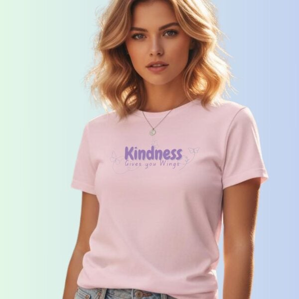 A woman wearing a pink coloured t-shirt with a butterfly design and the text "Kindness gives you wings".
