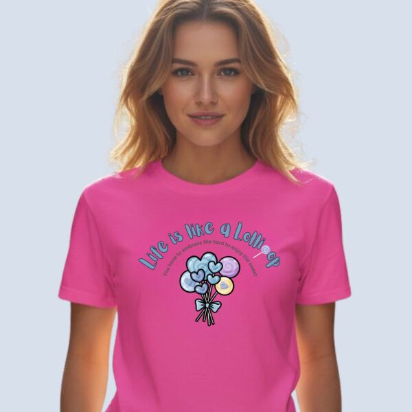 A woman wearing a charity pink coloured t-shirt with a lollipop design, the text "Life is like a Lollipop" and "you have to embrace the hard to enjoy the sweet".