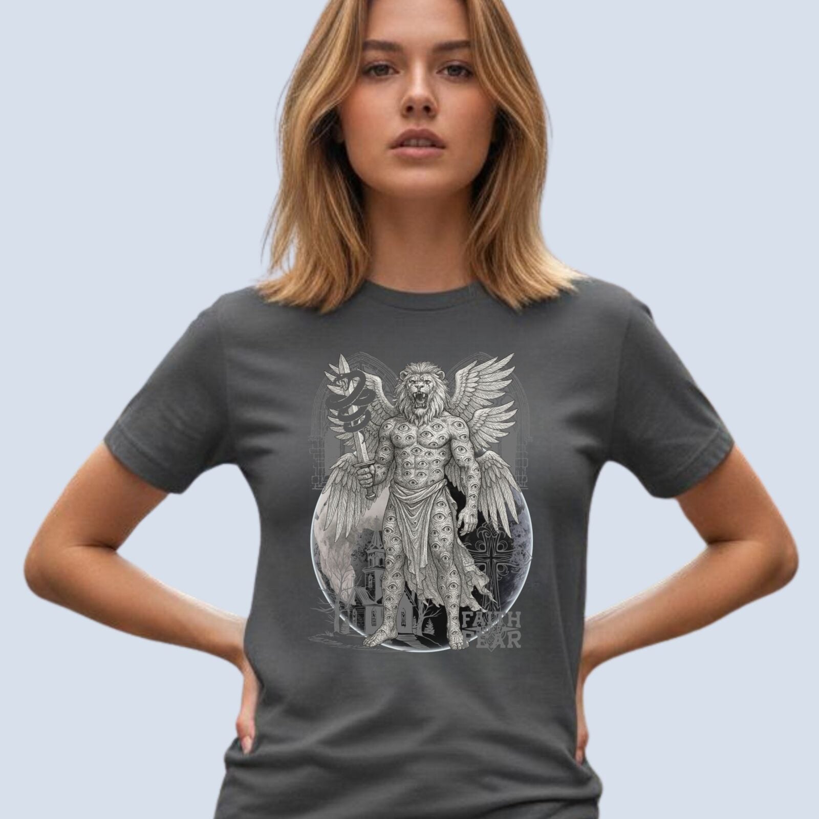A woman wearing a dark grey coloured Christian Gothic t-shirt that features a celestial man with a lion’s head and six wings, a church, a cross, the earth, and ornate Victorian arches. It also has text "Faith over Fear".