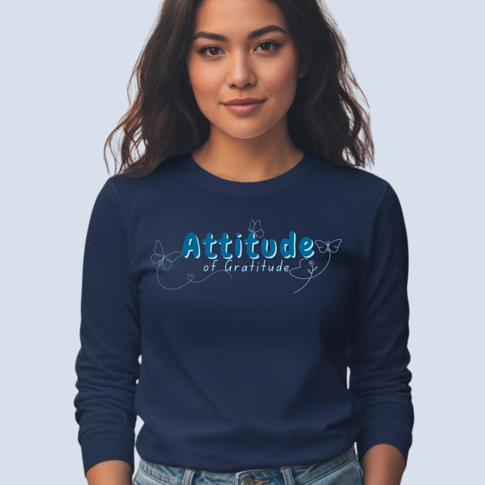 A woman wearing a navy coloured long sleeve t-shirt with a butterfly design and the text "Attitude of Gratitude".
