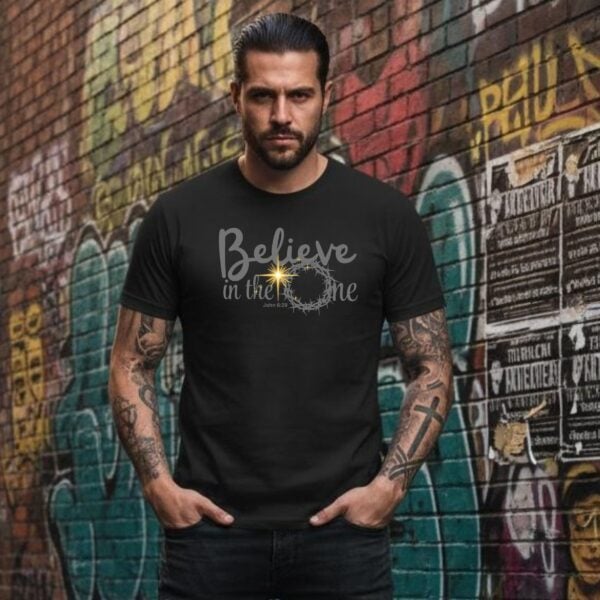 Believe in the One Tshirt Man with tattoos A man wearing a black unisex t-shirt with a religious design and the text "Believe in the One" relating to John 6:29.