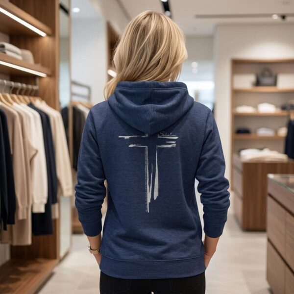 Salvation Cross Zip Hoodie Woman Navy A woman wearing a navy zip hoodie with a cross design printed on the back. This Christian Cross design includes the text "Salvation" and quote Galatians 3:11.