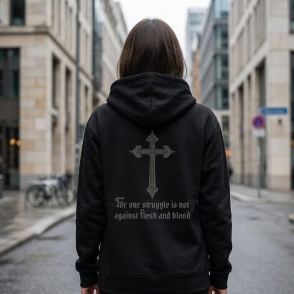 Copy of Struggle not Cross Zip Hoodie Front & Back A woman wearing a black unisex zipper hoodie with a cross design and the text "For our struggle is not against flesh and blood" printed on the back of the hoodie.