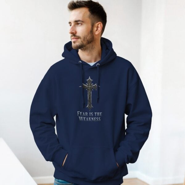 A man wearing a black unisex pullover hoodie with a cross design and the text "Fear is the Weakness".