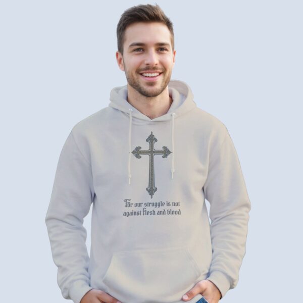 A man wearing a sand coloured unisex pullover hoodie with a cross design and the text "For our struggle is not against flesh and blood".