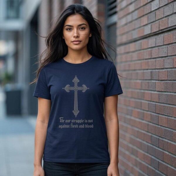 A woman wearing a navy unisex t-shirt with a cross design and the text "For our struggle is not against flesh and blood".