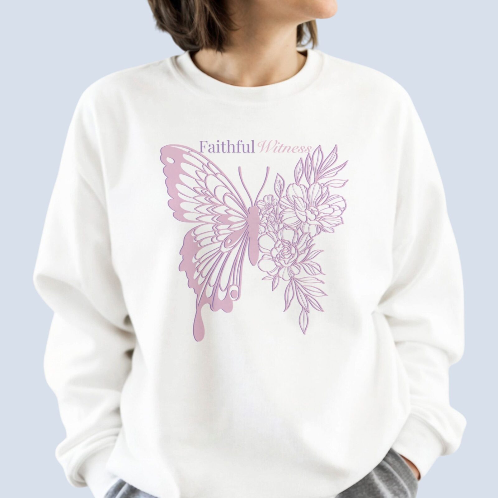 A woman wearing a white sweatshirt with a butterfly and flower design and the text "Faithful Witness" on the front of the sweatshirt.