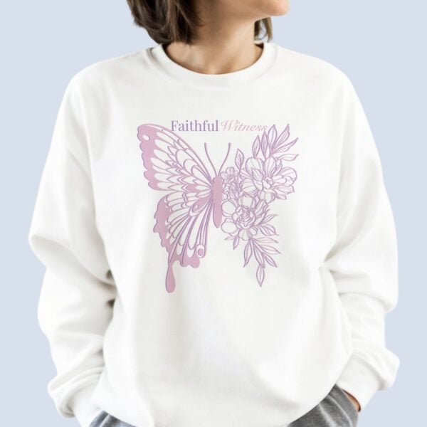 A woman wearing a white sweatshirt with a butterfly and flower design and the text "Faithful Witness" on the front of the sweatshirt.