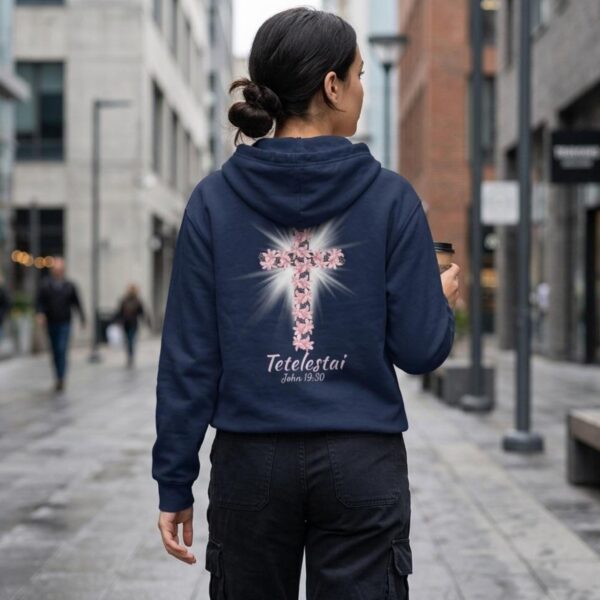 Lily Cross Zip Hoodie Back Woman Walking A woman wearing a navy zipper hoodie featuring a lily cross design with the text "Tetelestai, John 19:30" printed on the back of the zip hoodie.