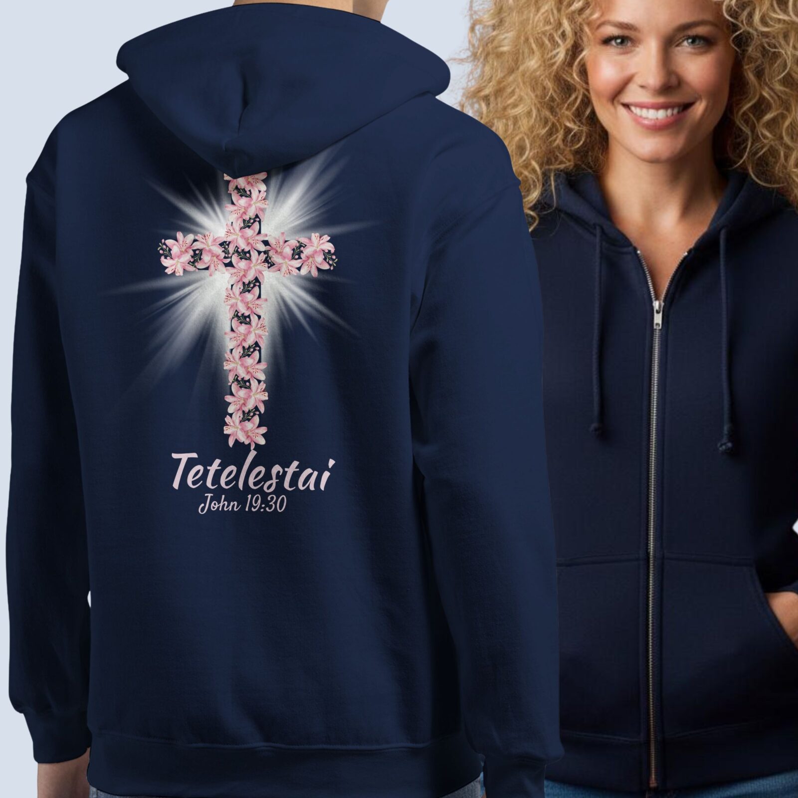 Two women wearing a navy zipper hoodie with a cross and lily design with the text "Tetelestai, John 19:30" on the back, showing the front and back of the zip hoodie.