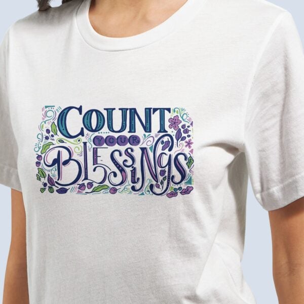 A woman wearing a white t-shirt with a colourful design and the text "Count your Blessings".