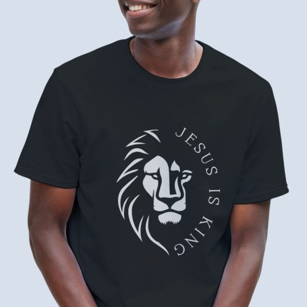 A man wearing a black unisex Christian t-shirt featuring a powerful lion design and the declaration “Jesus is King”, printed on the front of the t-shirt.