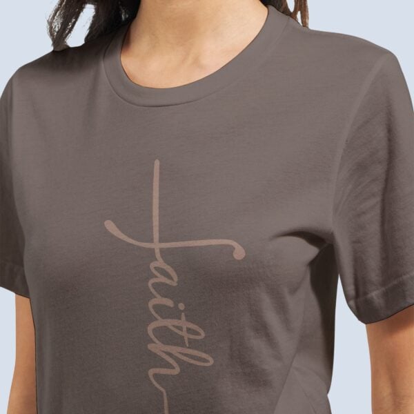A woman wearing a pebble brown Christian t-shirt with the word faith, written in such a way to form a cross. This faith cross shirt for women is a minimalist Christian tee design that comes in 11 colour options.