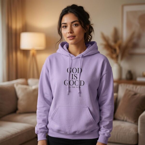 A woman wearing a soft purple unisex pullover hoodie with the text "God is Good all the time" printed on the front.