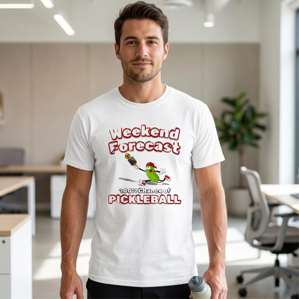 A man wearing a white t-shirt featuring a pickle playing pickleball and the phrase "Weekend Forecast – 100% Chance of Pickleball."
