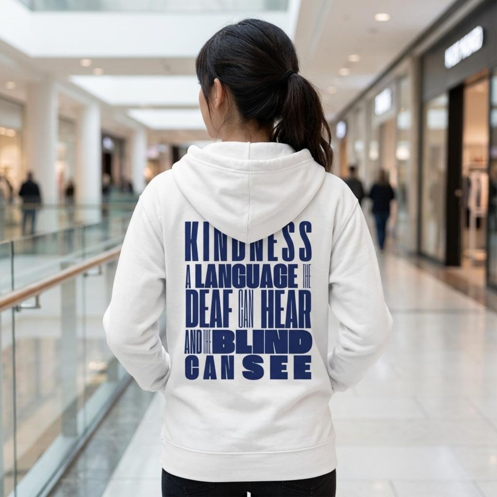 A woman wearing a white unisex full zip up hoodie with an inspirational message "Kindness, a language the deaf can hear and the blind can see". The design on this Christian hoodie is printed on the back of the hoodie only.
